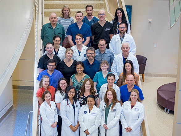 The Pediatrics Department in white coats and scrubs posing on stair steps.