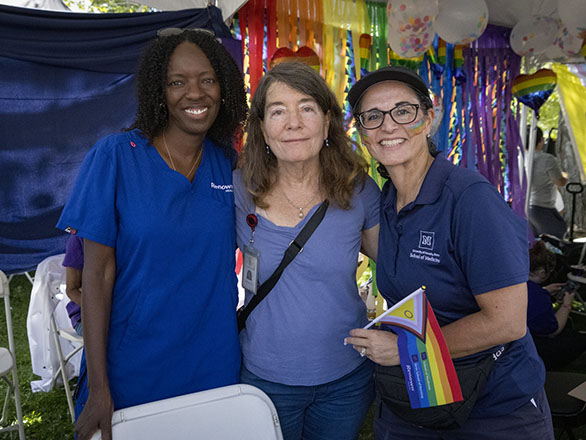 Three women at Northern Nevada Pride at the UNR Med and Renown booth smiling.