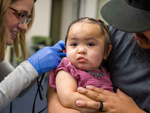 An audiologist looks a baby's ear in a clinic