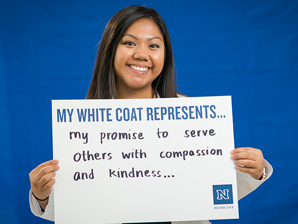 Student Holding a sign that says My White Coat Represents My Promice to serve others with compassion and kindness