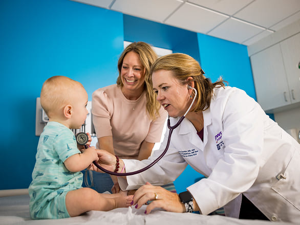 A baby is examined by a doctor while Mom watches