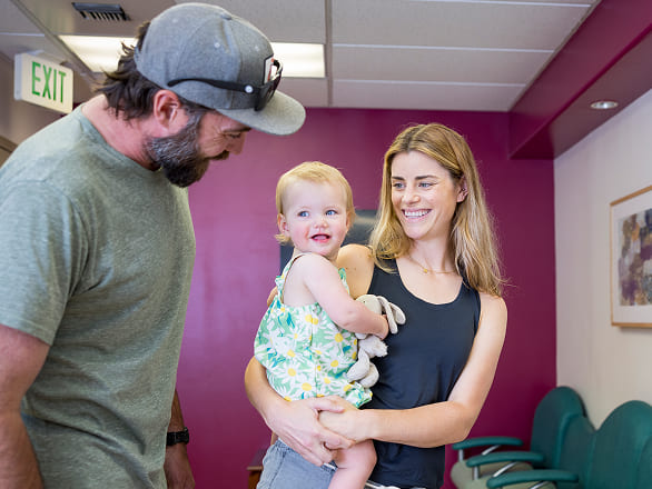 Two smiling parents hold their happy baby