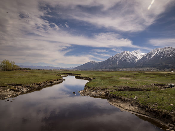 A river winds its way through verdant rural Nevada fields to the horizon