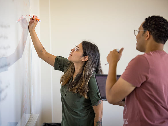 Data scientists collaborate at a whiteboard