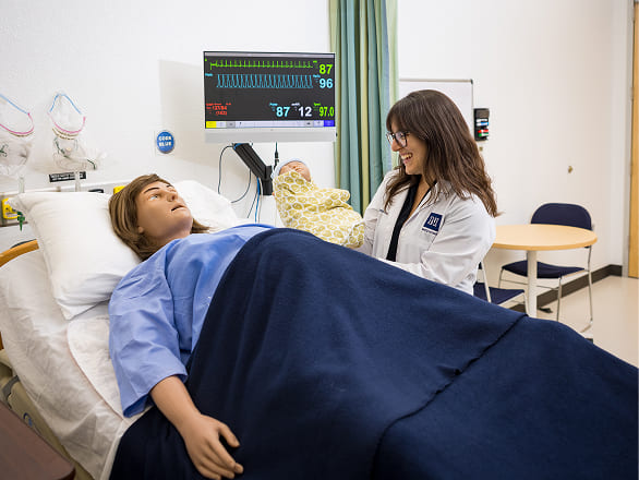 A medical student presents a simulated baby to its simulated mother