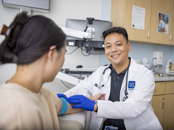 A smiling doctor gets ready to do a blood draw on a patient