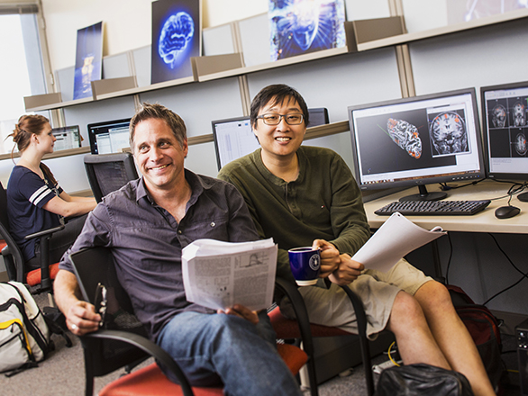 Two men sitting together and doing research on a computer.