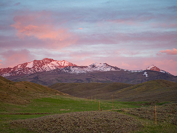 Sunset over mountains and grassy fields.