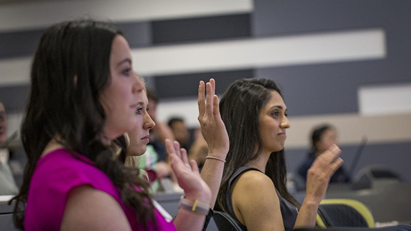 A group of women seated in a room raising their hands