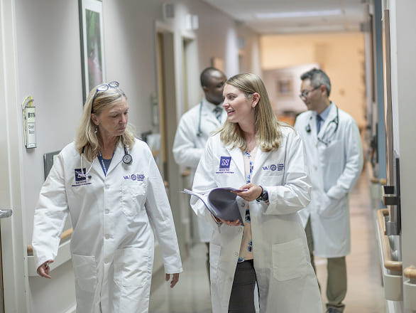 Doctors and med students walking and talking a hospital hallway