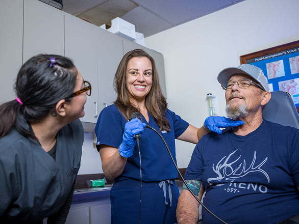 Two med students address a patient at a speech pathology and audiology clinic