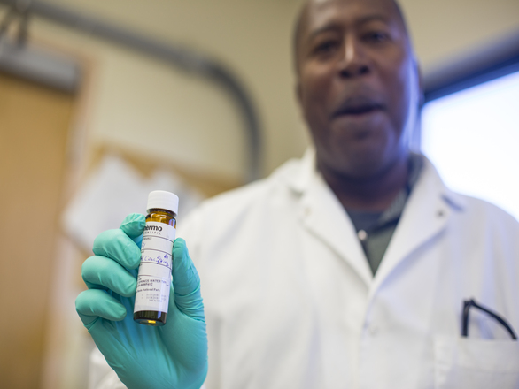 A man in a lab coat holding a glass vial