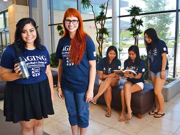 Students in University of Nevada, Reno shirts standing in an atrium smiling at the camera