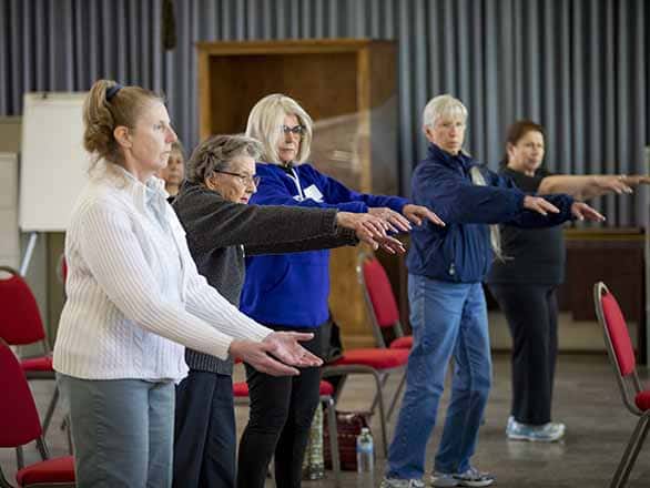 older adults standing in a line while balancing