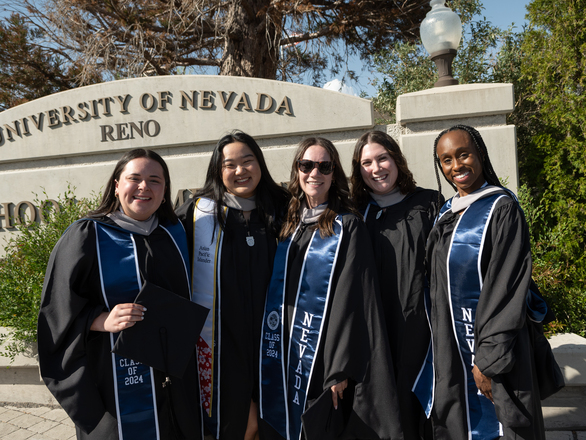 Graduate medical students posing in front of the University of Nevada, Reno School of Medicine sign