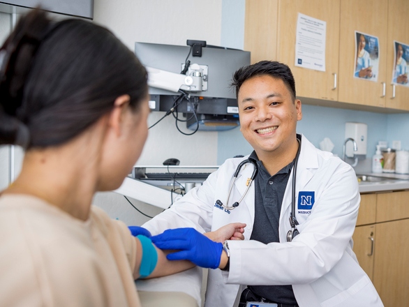 A Medical student examines a patient's arm during a medical consultation in a clinical setting.