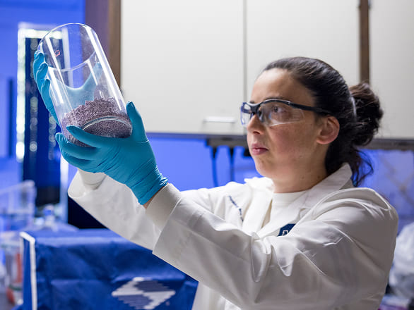 A med student examines a beaker full of something blue