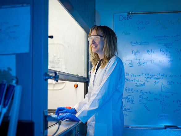 A med student works in a lab next to a ventilation hood