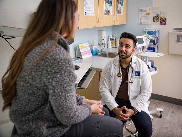 A doctor sits while talking to a patient in a clinic