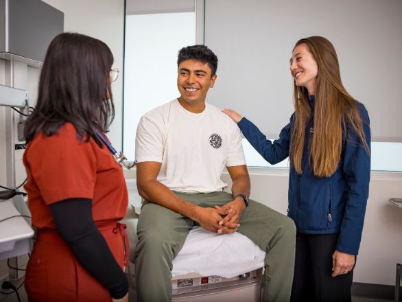 Two physician assistants interacting with a patient in a clinical setting