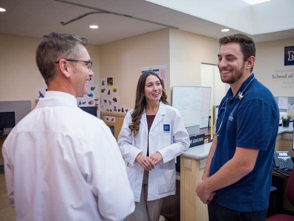 Physician assistant professor mentoring two students in a clinical setting