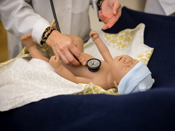 Medical instructor demonstrating how to check baby's heart rate using a stethoscope
