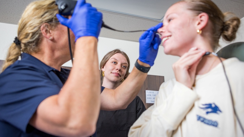 A Speech Pathology and Audiology student observes a faculty member examining a patient