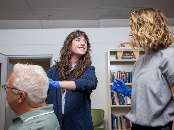 A Speech Pathology and Audiology student engages with a patient under the guidance of a faculty member