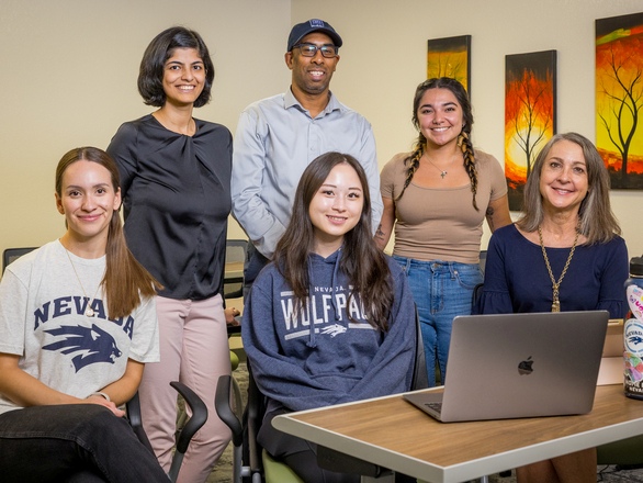 Speech Pathology and Audiology students and faculty members smiling for a photo in front of a laptop, showcasing teamwork and collaboration.