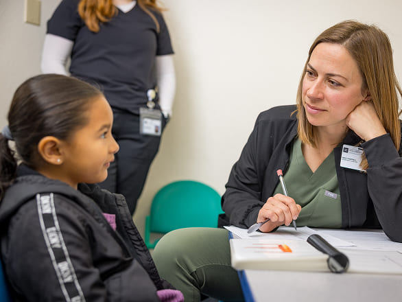 A doctor talks with a young patient at a clinic