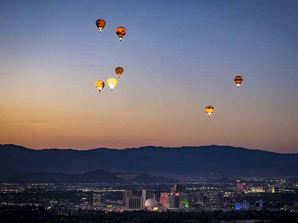 Shot of Downtown Reno with hot air balloons in the sky at dawn.