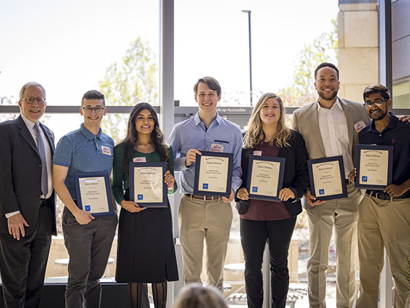 Medical students posing with Dean Paul J. Hauptman with award plaques they received.