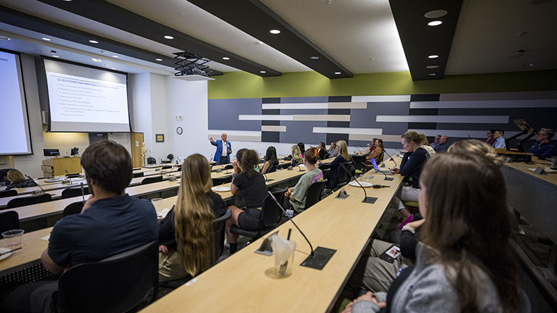 A faculty member talking to a room full of students.