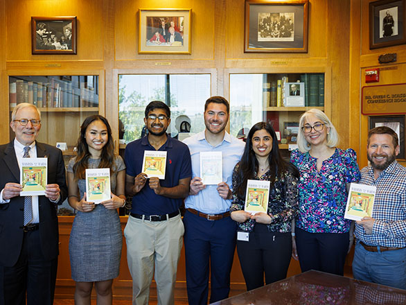 Medical students holding a book of stories they published.