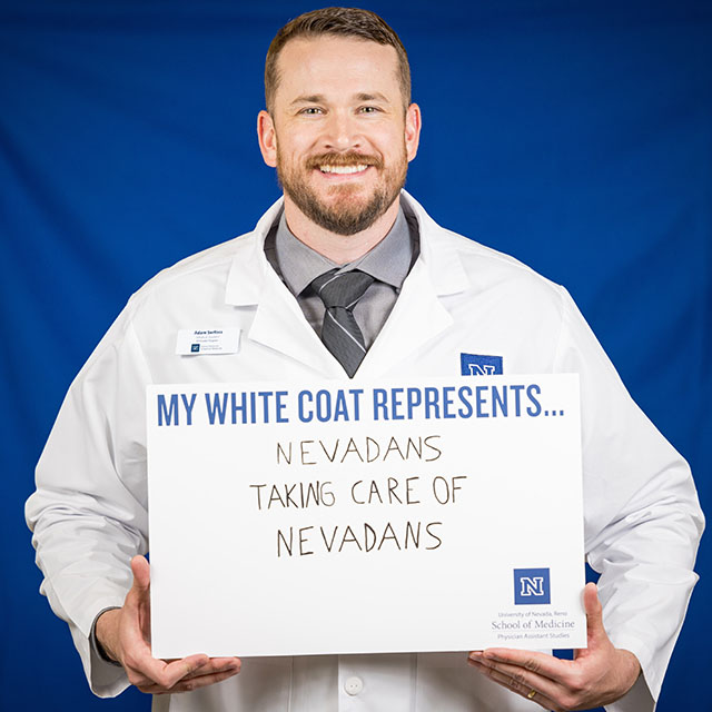 Adam Serfoss holding a sign that reads, "My White Coat represents... Nevadans taking care of Nevadans."