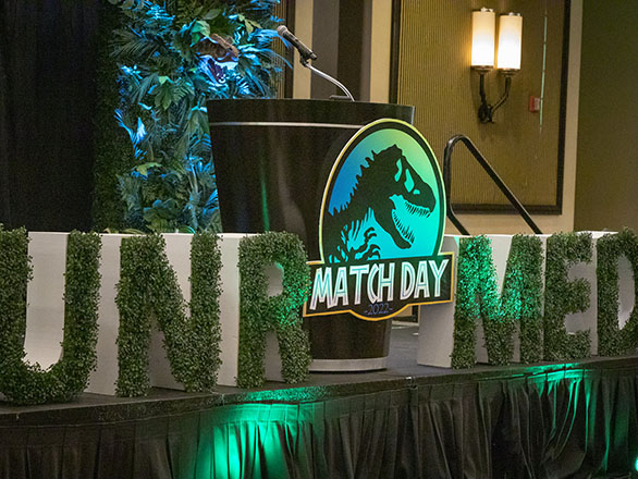 Stage with podium with Jurassic Park logo and UNR Med letters.