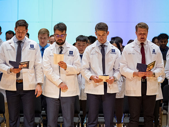 M.D. students reciting the Physician's Oath on stage.