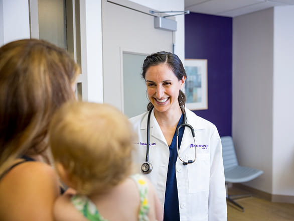 A Renown provider smiles at a mother and child who have entered the clinic